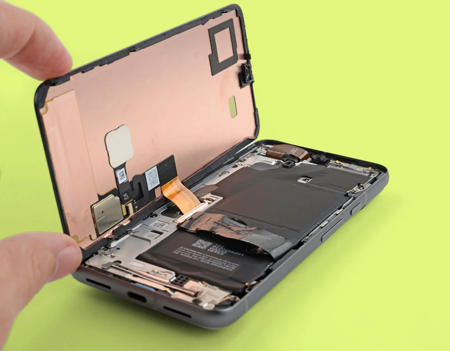 Someone holding a new iPhone screen above the open iPhone frame