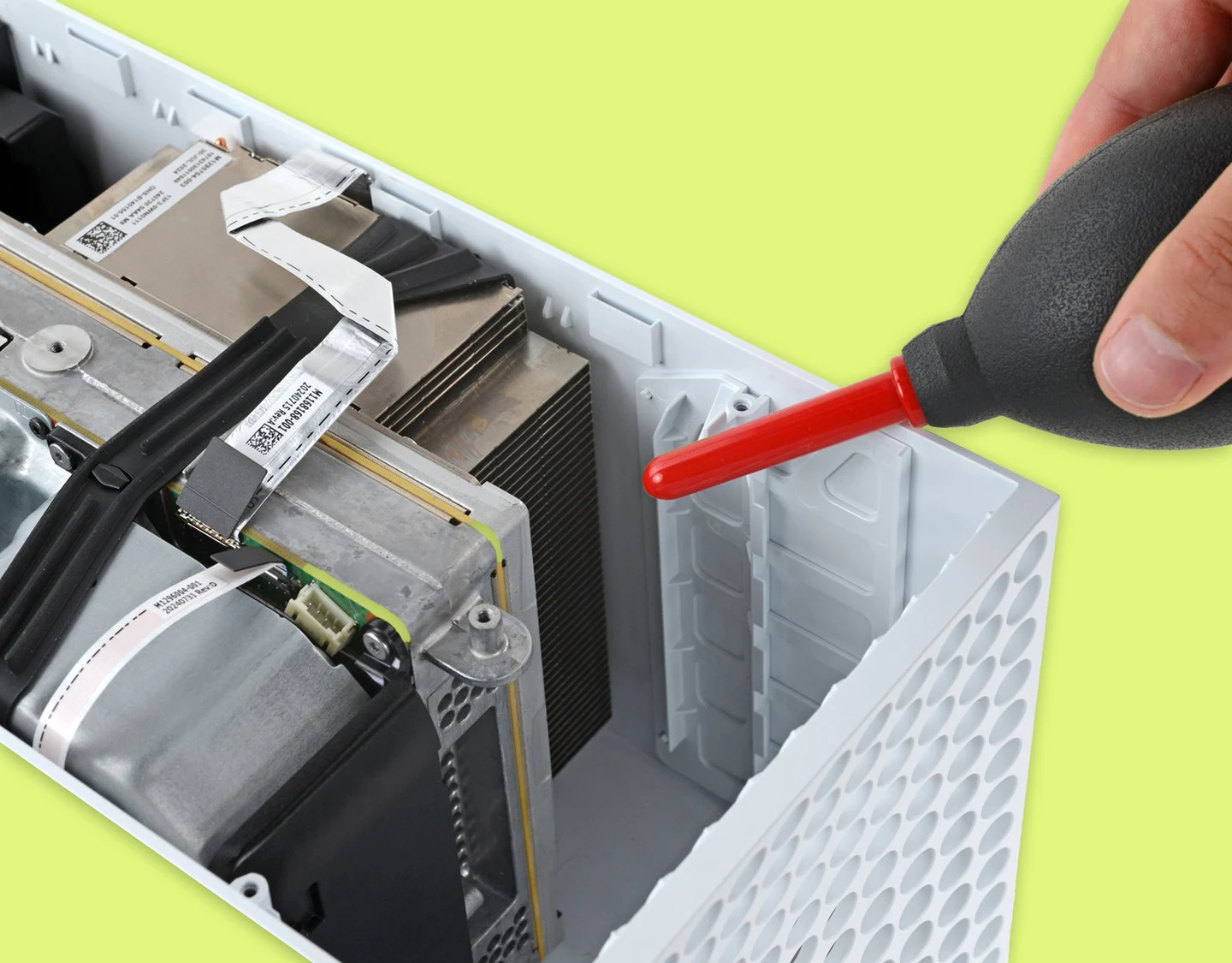 A person using compressed air on the Xbox Series S vents to clean internal components