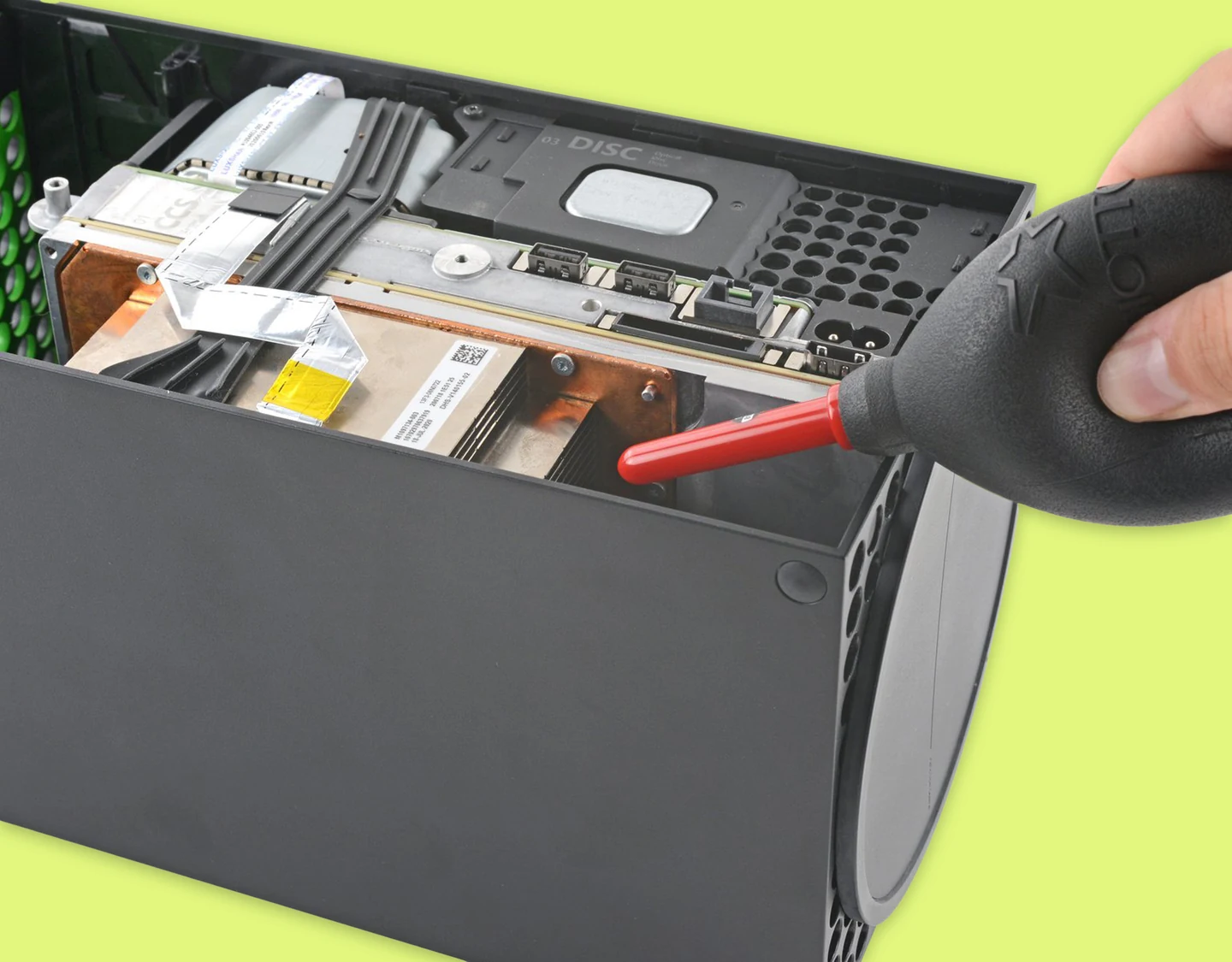 A person using compressed air to clean the Xbox Series X heatsink
